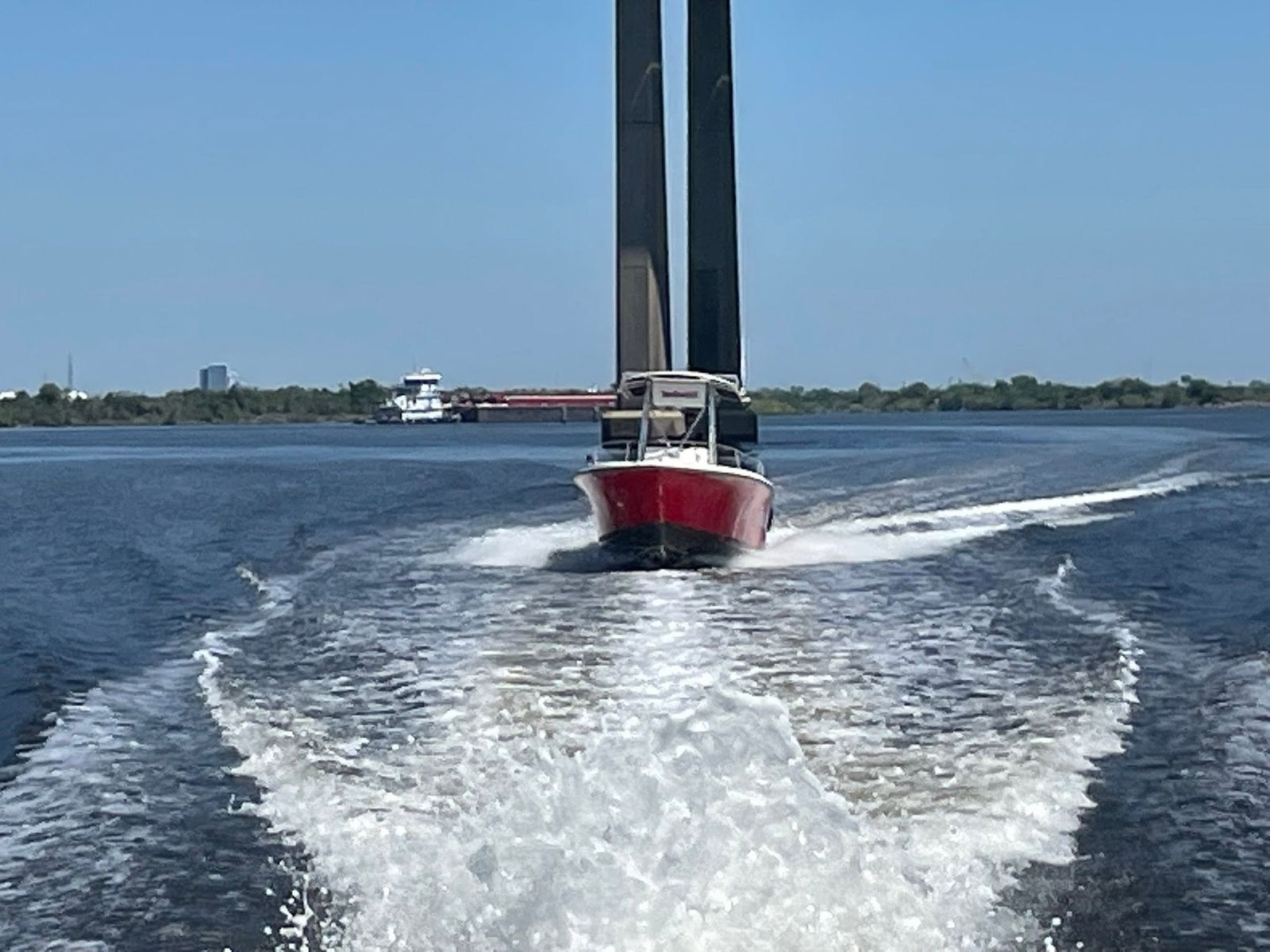 A red and white TowBoatUS service vessel with tall towing mast approaches through Sabine Lake waters on a clear day.