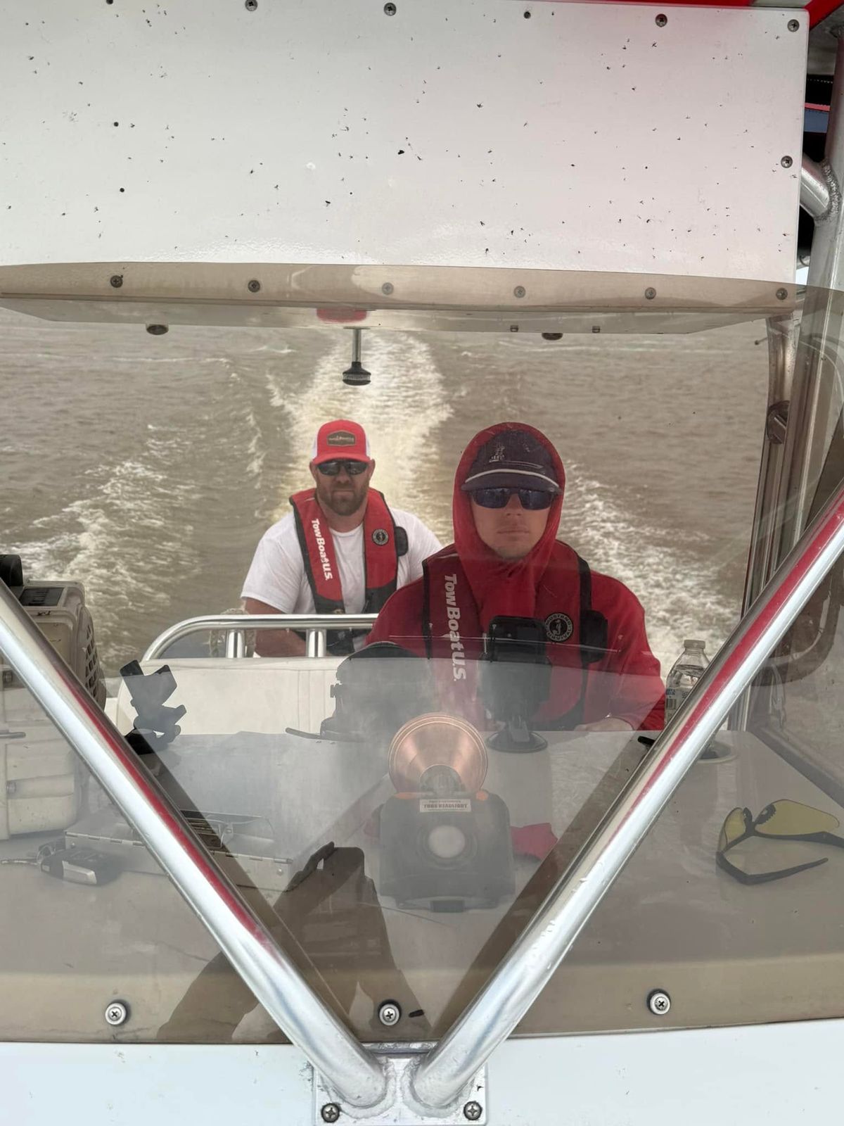 Two TowBoatUS Sabine Lake crew members in red branded gear operating a tow vessel on Sabine Lake.