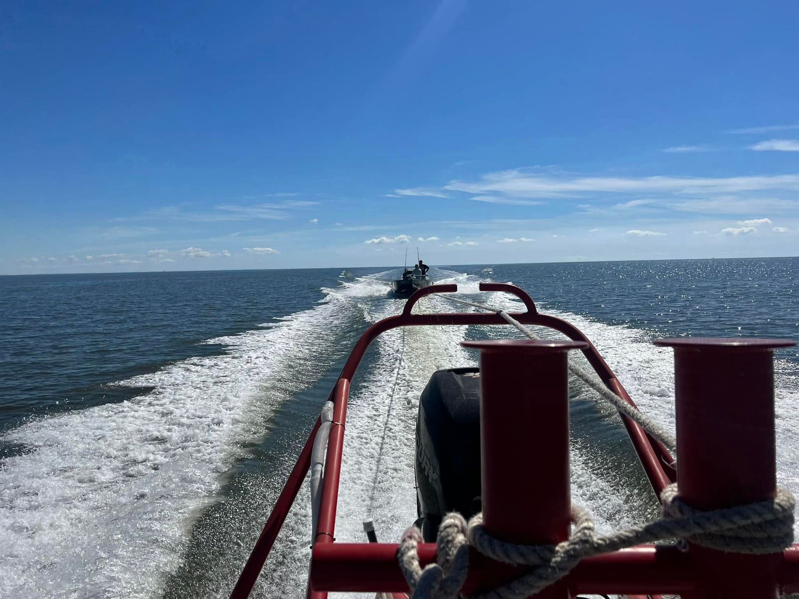 A TowBoatUS vessel towing a disabled boat on Sabine Lake under clear skies.