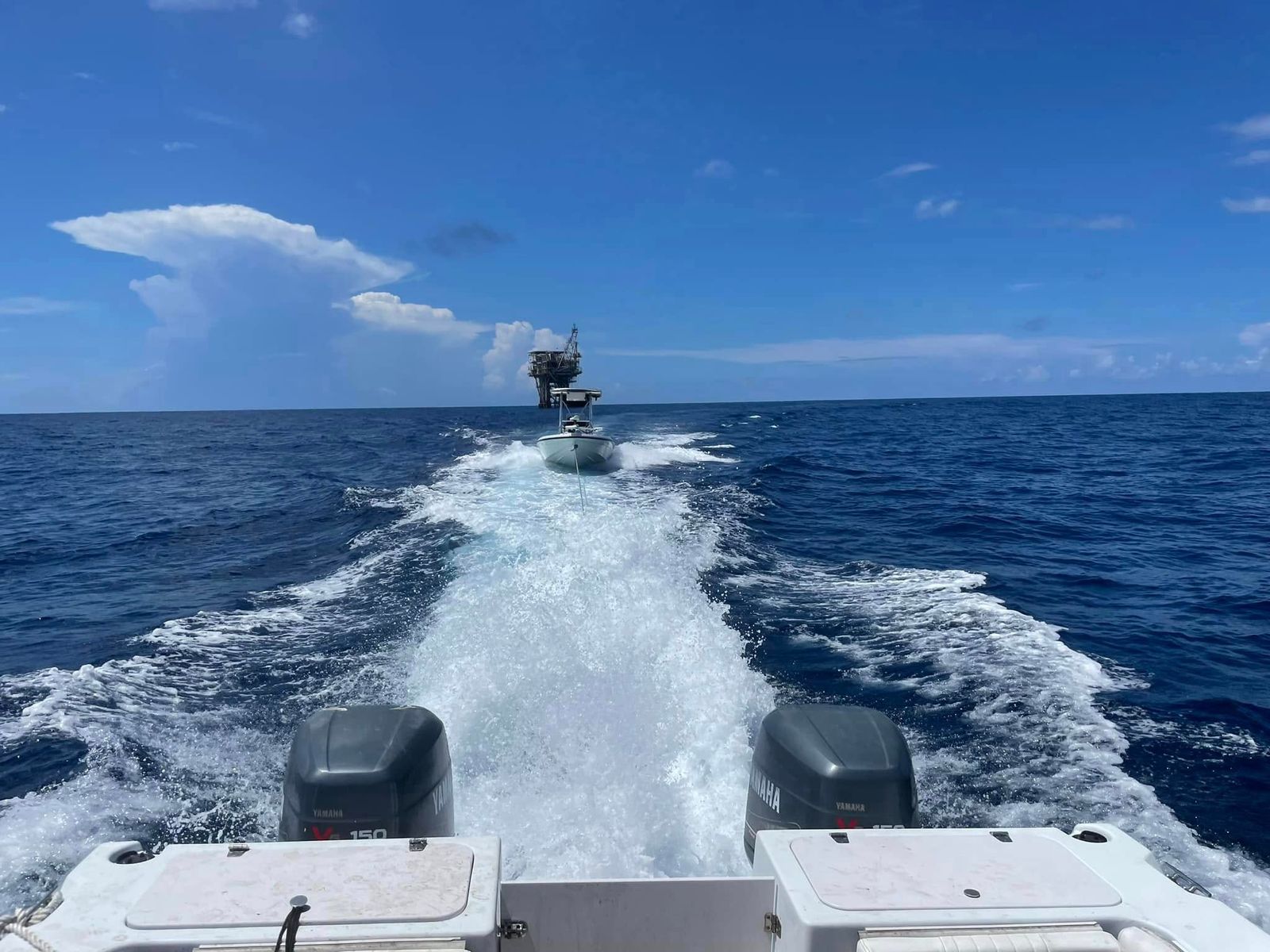 A TowBoatUS Sabine Lake service vessel towing another boat across the open water of Sabine Lake under clear blue skies.