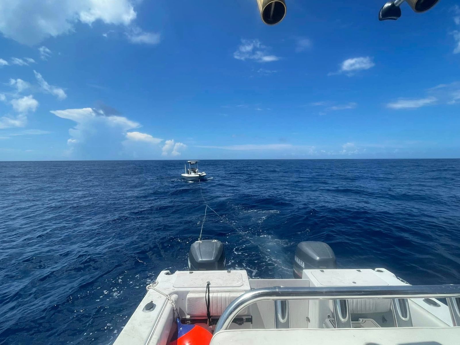 A TowBoatUS rescue vessel approaches another boat on Sabine Lake under clear blue skies.