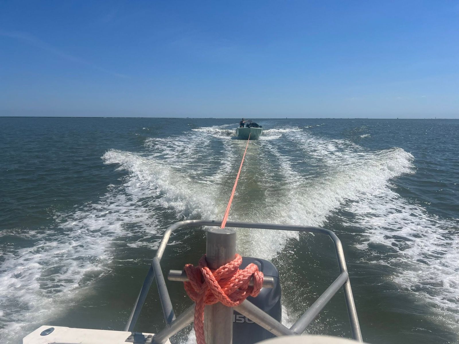 A towboat from TowBoatUS Sabine Lake tows a vessel through choppy waters on Sabine Lake under clear skies.