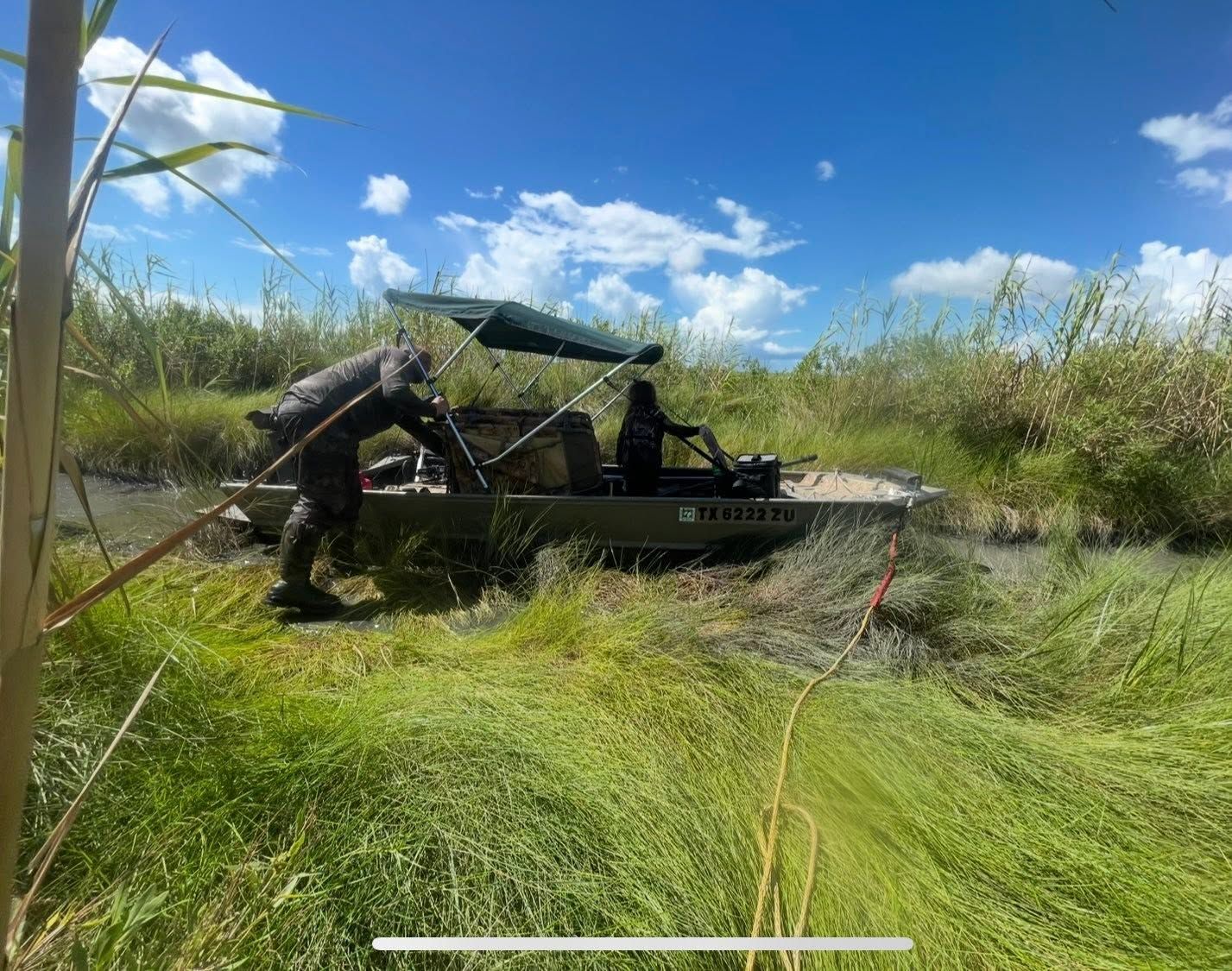 A TowBoatUS Sabine Lake airboat with operators aboard among the marsh grasses.